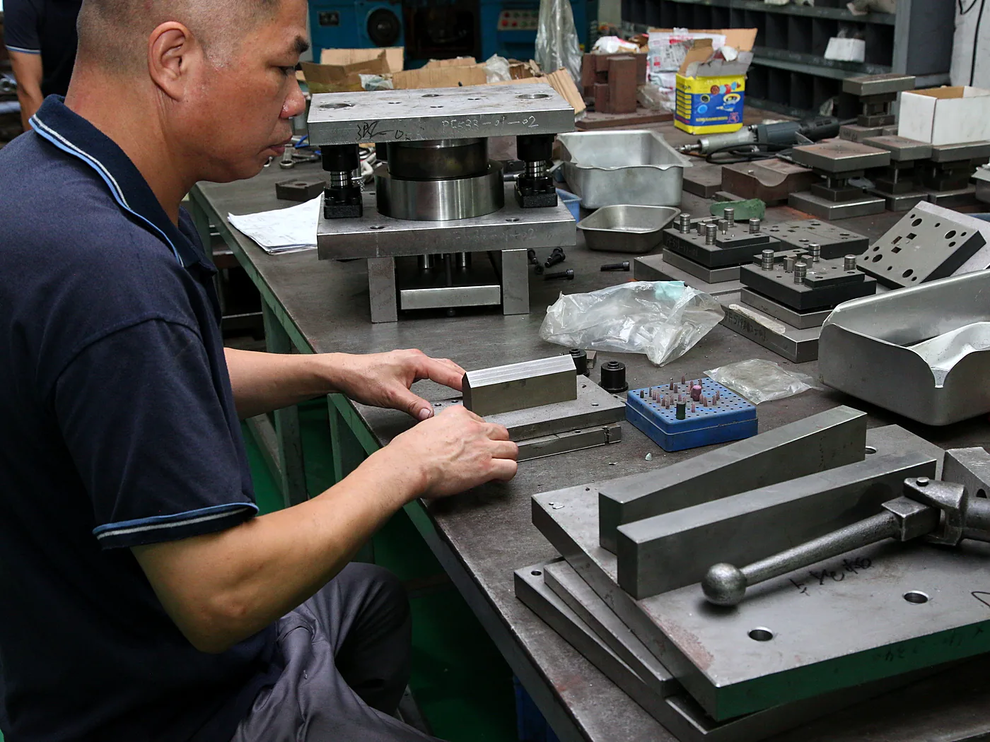 Assembler fitting machined brackets at a workbench vise