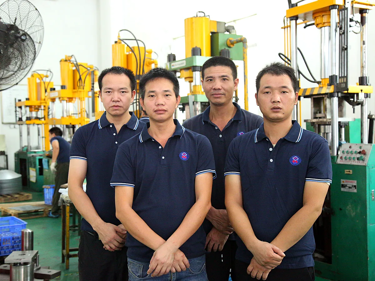 Five production staff in uniform in front of a press